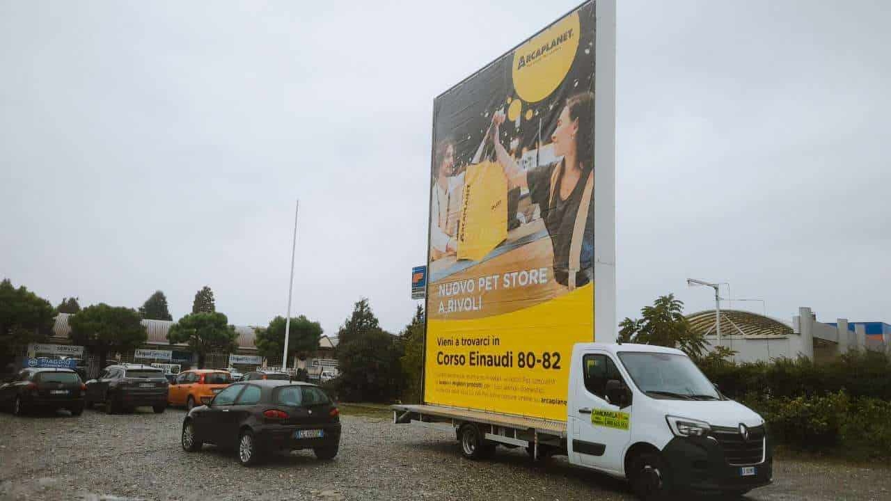 Camion vela pubblicitario Arcaplanet con grafica gialla parcheggiato in un piazzale a Rivoli
