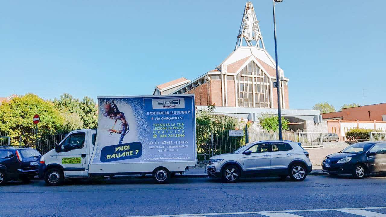 Camion vela con campagna Dance Studio parcheggiato davanti a una chiesa