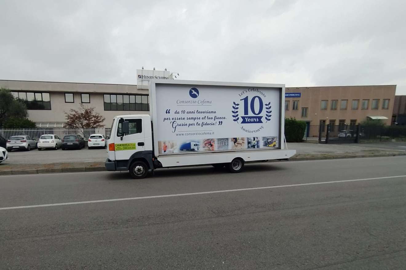 Camion vela pubblicitario celebra i dieci anni di un consorzio lungo una strada industriale